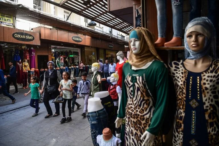 A Syrian woman and her children walk on a street near shops in Gaziantep, in the south-west province of Turkey. (AFP)