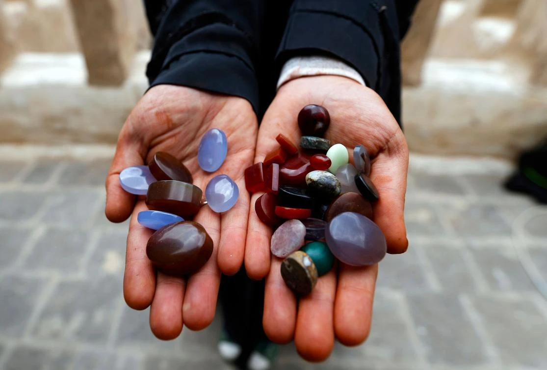 Safa al-Faqih, one of the few female Yemeni craftsmen working in the precious stones industry in Yemen, holds precious stones in the old city of the capital, Sanaa, on April 18, 2018. (AFP)