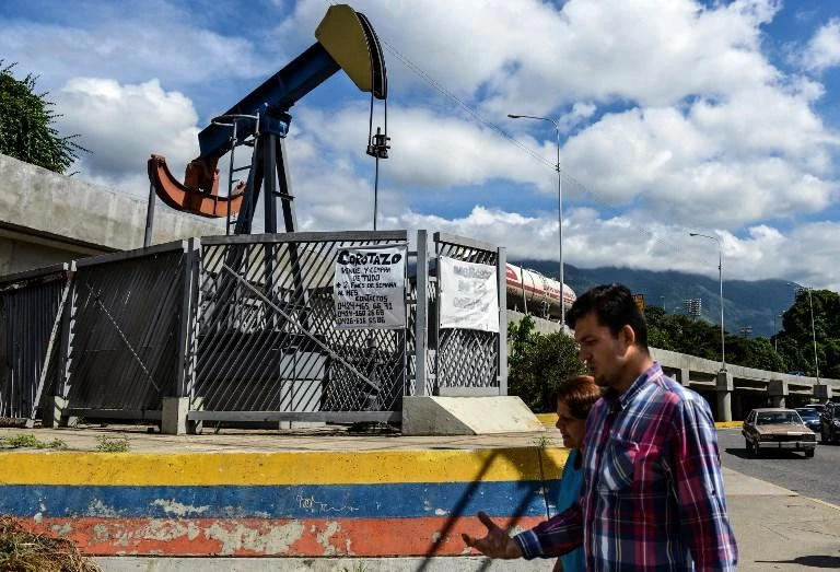 People walk by a small square with an oil pump in one of the access roads to the Central University of Venezuela, in Caracas. (AFP)