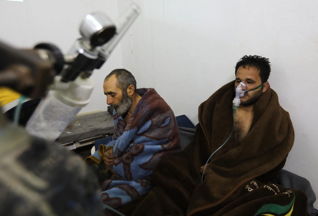 Syrians suffering from breathing difficulties following Syrian regime air strikes on the northwestern town of Saraqeb rest around a stove at a field hospital in a village on the outskirts of Saraqeb (Omar Hajj Kadour/AFP)