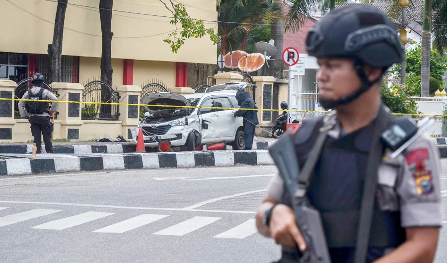 Police stand guard as a car that was used to attack the police headquarters is examined in Pekanbaru, Indonesia. (AFP)