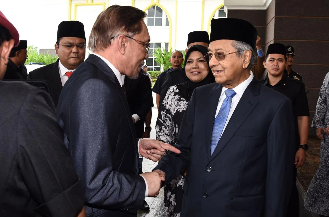 Malaysia’s Prime Minister Mahathir Mohamad, right, shakes hands with former opposition leader Anwar Ibrahim following his release from custody at National Palace in Kuala Lumpur. (Department of Information via AFP)