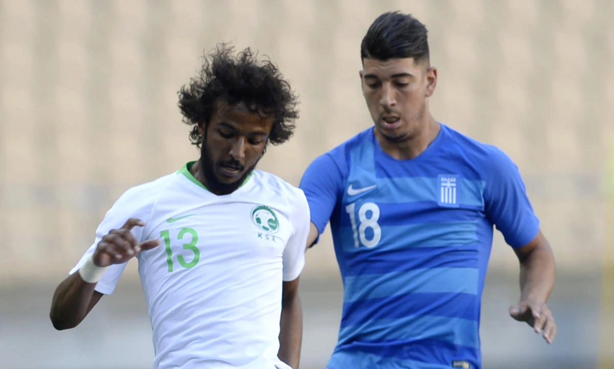 Saudi Arabia defender Yasser Al-Shahrani fights for the ball with Greece's Dimitrios Limnios.