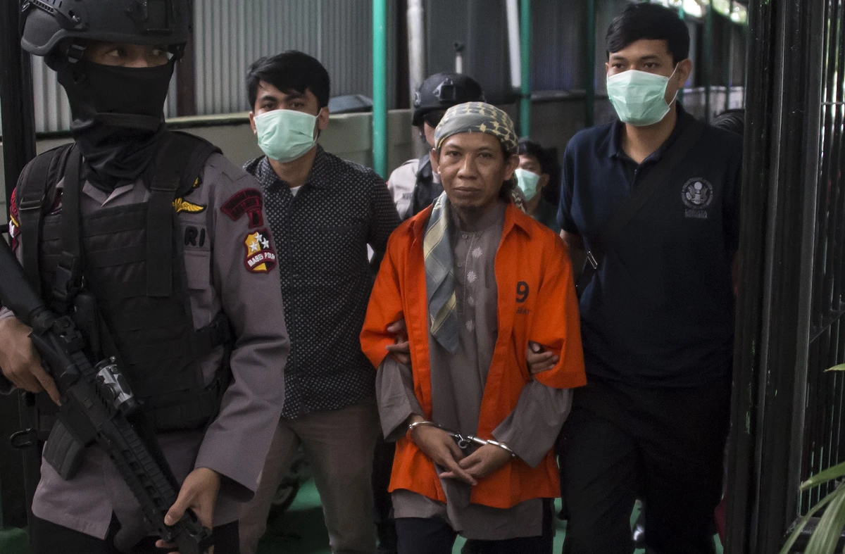Indonesian armed police escort Indonesian radical cleric Aman Abdurrahman (2nd R) as he arrives at the South Jakarta court in Jakarta on February 15, 2018. (AFP)