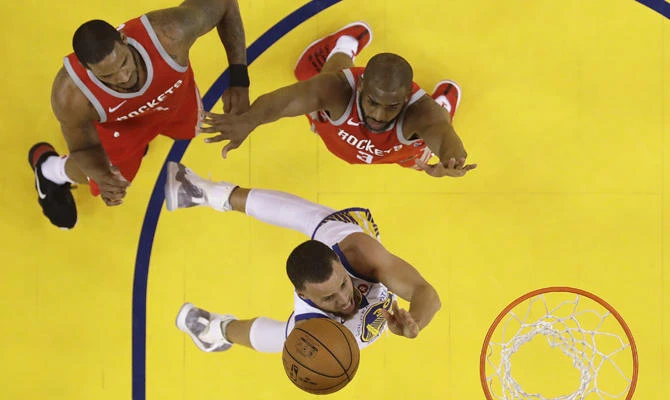 Golden State Warriors' Stephen Curry, bottom, drives past Houston Rockets' Chris Paul, right, and Trevor Ariza, top left, during the first half in Game 3 of the NBA basketball Western Conference Finals on May 20, 2018, in Oakland, California. (AP Photo/Marcio Jose Sanchez)
