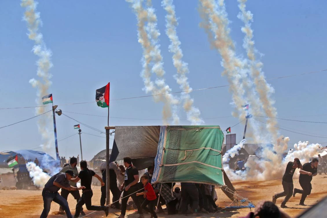 Palestinians run for cover from tear gas near the border between Israel and the Gaza Strip, east of Jabalia on May 14, 2018. (AFP)