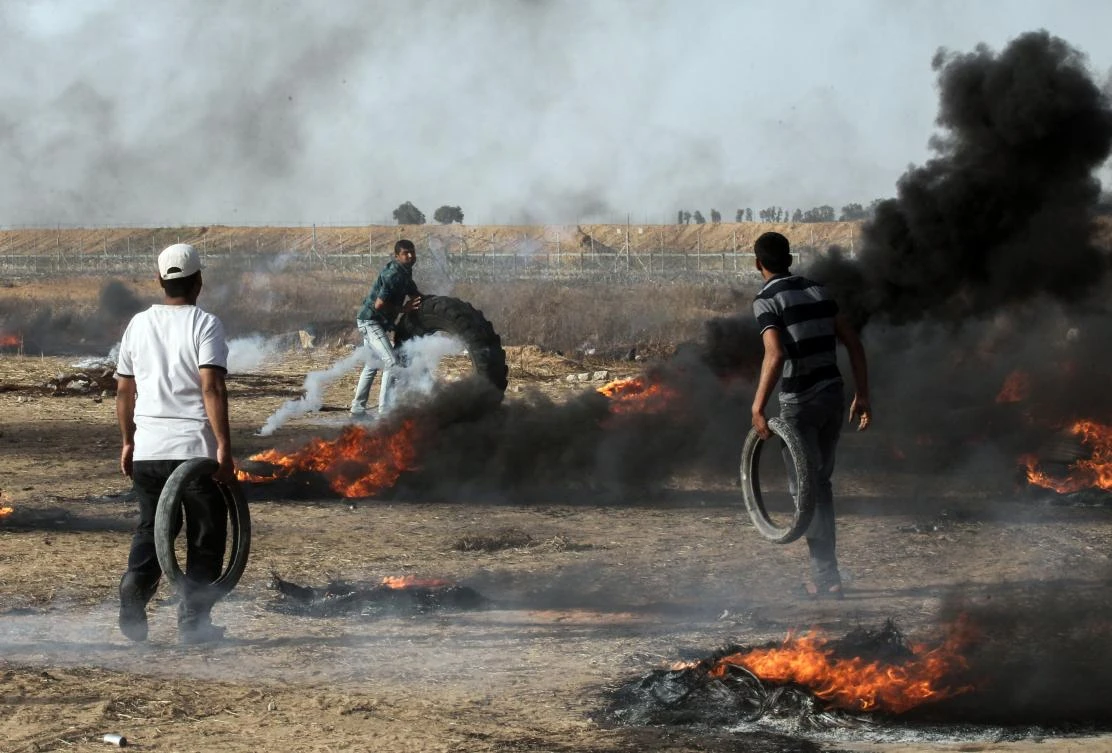Palestinian demonstrators burn tires during clashes with Israeli forces along the border with the Gaza strip east of Khan Yunis on May 18, 2018. (AFP)