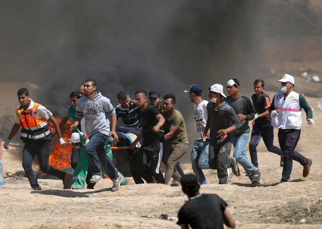 Palestinians carry a demonstrator injured during clashes with Israeli forces near the border between the Gaza strip and Israel east of Gaza City. (AFP)