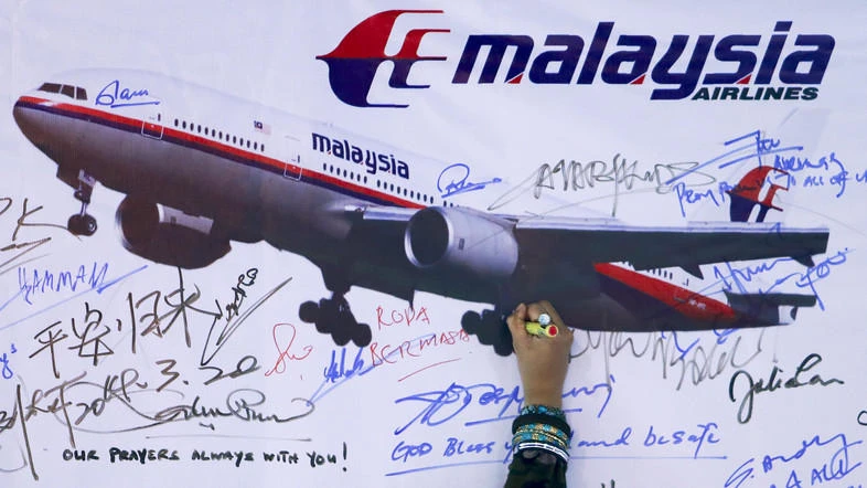 Malaysia Airlines Flight MH370, carrying 239 people, disappeared en route from Kuala Lumpur to Beijing on March 8, 2014. Above, a woman writes a message on a board for passengers of the missing Flight MH370 and their family members in this March 2014 photo. (Reuters)