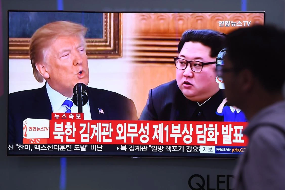 A man walks past a television news screen showing North Korean leader Kim Jong Un, right, and US President Donald Trump at a railway station in Seoul. Pyongyang has renewed its threat to pull out of a summit next month with President Donald Trump. (AFP)