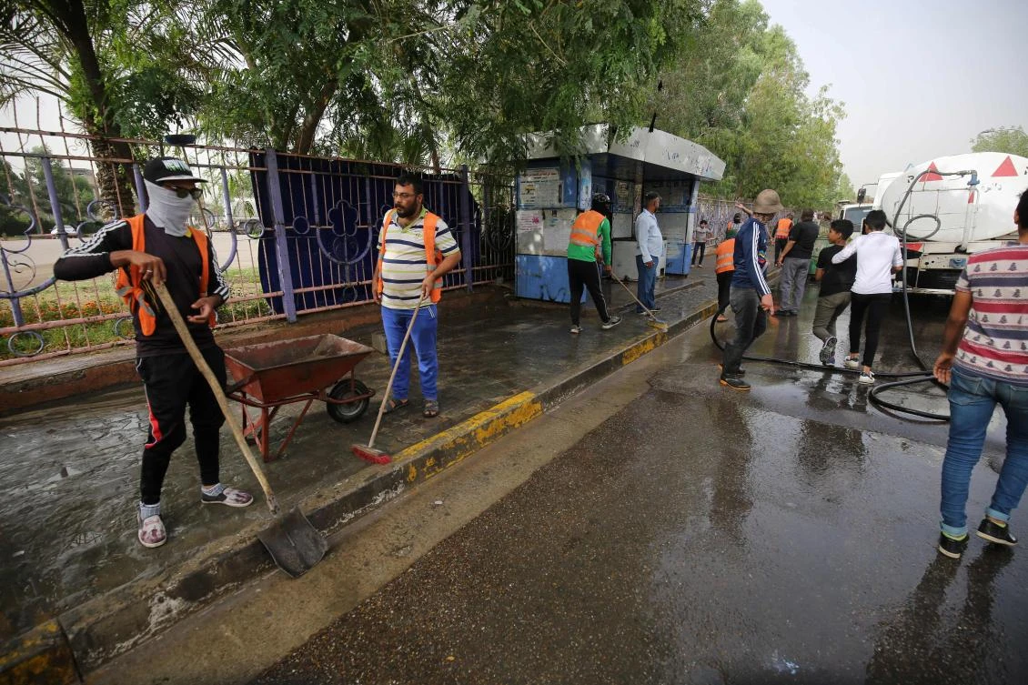 Iraqi municipal workers clean the site of an overnight suicide bomb attack in Baghdad's Shiite suburb of Al-Shoala on May 24, 2018. (AFP)