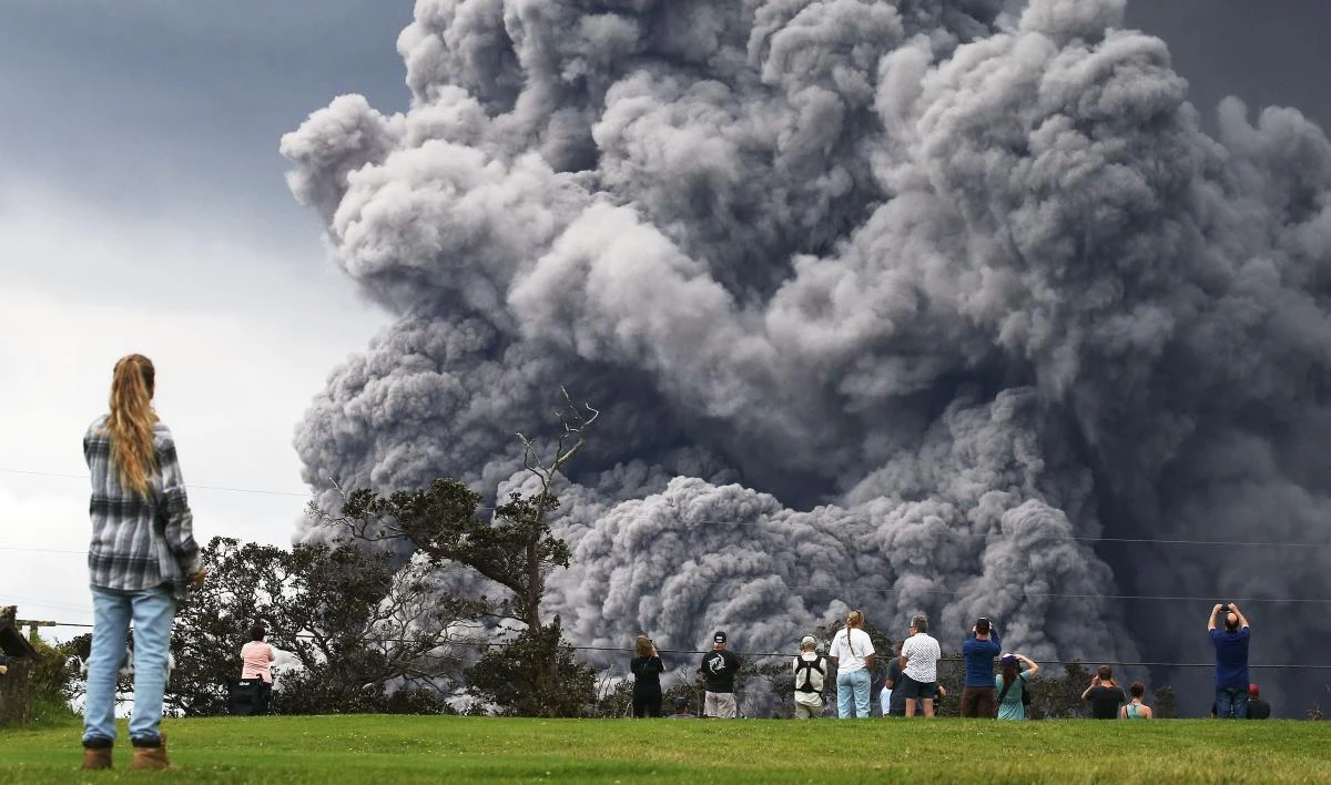 People watch at a golf course as an ash plume rises in the distance from the Kilauea volcano on Hawaii's Big Island on May 15, 2018 in Hawaii Volcanoes National Park, Hawaii.(AFP)