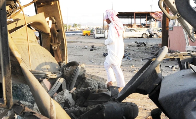 A Saudi man walks past wreckage at a market for vehicles on Aug. 27, 2016 in Najran, a week after it was struck by a rocket fired from Yemen. AFP