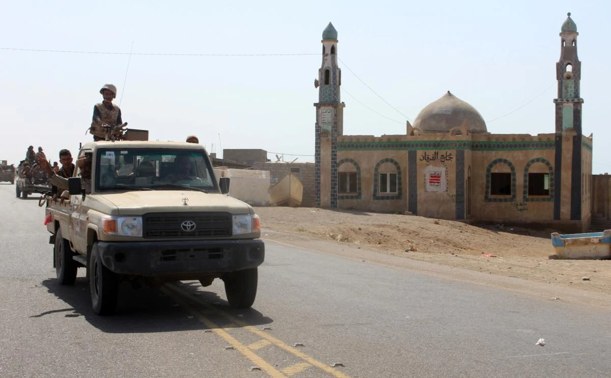 Yemeni fighters loyal to the Saudi-backed Yemeni president riding in the back of a pickup truck past a mosque. (AFP)