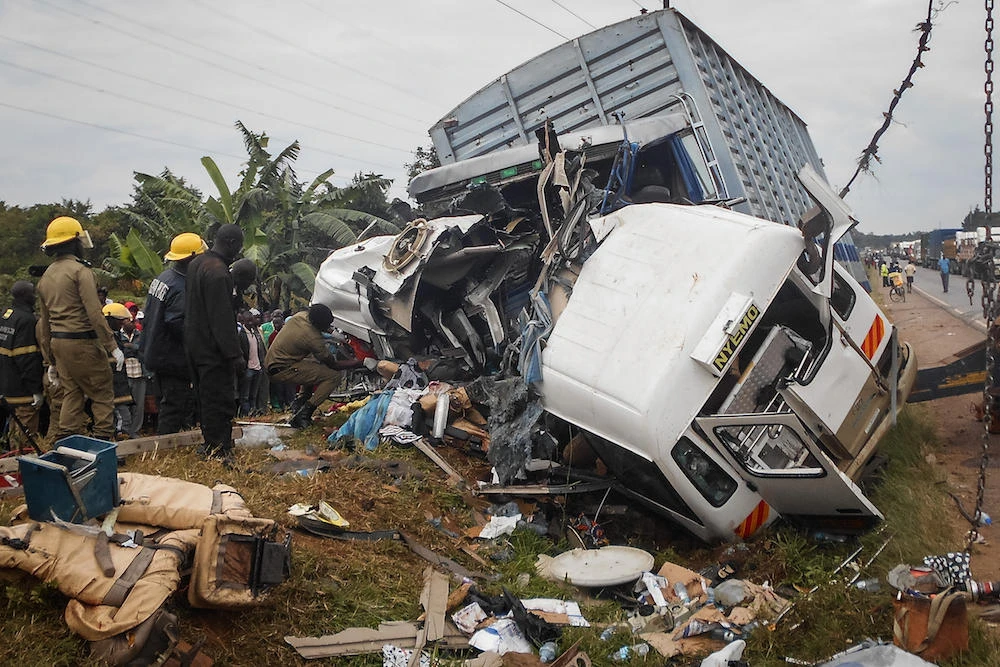 Police officers work on the site of a accident between a truck and a bus, resulting in 14 deaths and 17 injuries, on a highway in Kampala on September 17, 2017. (File photo: AFP)