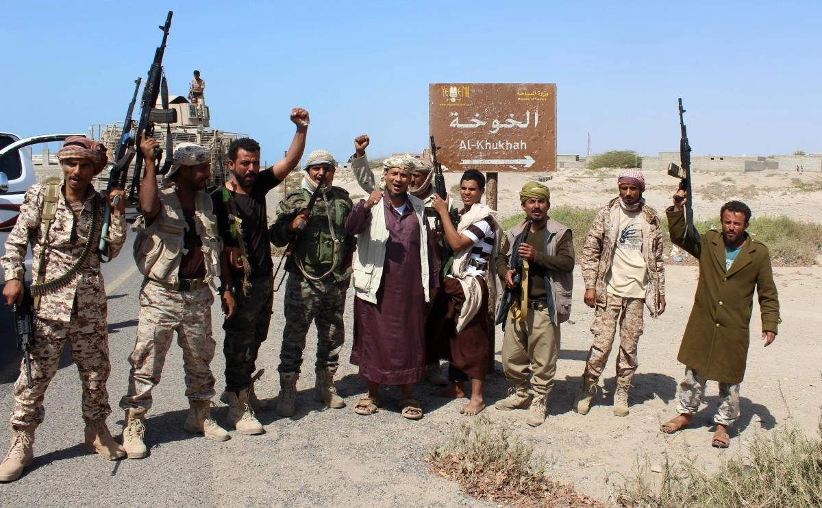 Yemeni fighters loyal to the Saudi-backed Yemeni president gesturing and shout slogans as they stand on a road leading to the town of Khokha. (AFP)