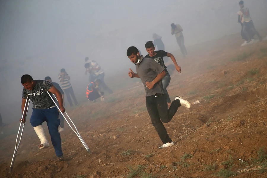 Palestinians run for cover from tear gas shot by Isreali forces during a demonstration along the border between Israel and the Gaza strip, east of Gaza City. (AFP)