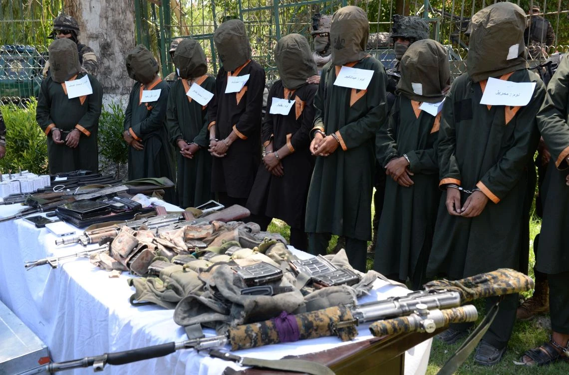 Taliban fighters stand handcuffed near seized weapons as they are presented to media in Jalalabad on May 22, 2018. (AFP)