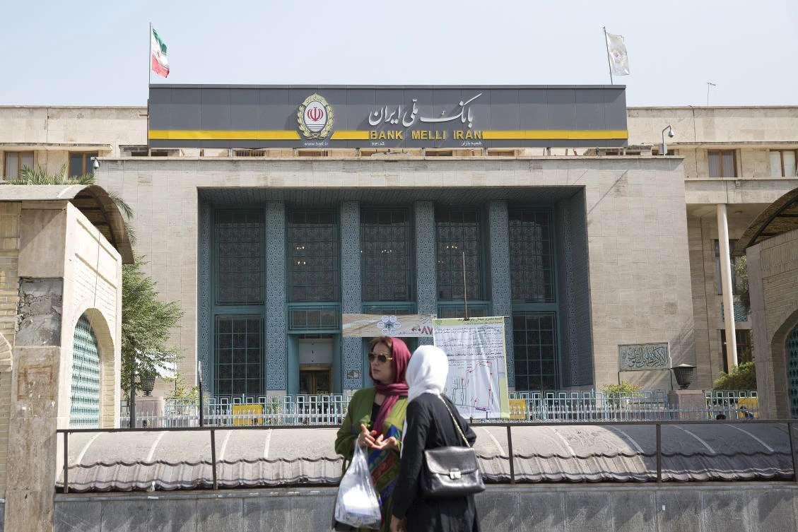 Pedestrians stand outside the Grand Bazaar outside a Bank Melli Iran Inc. bank branch in Tehran. (Getty)