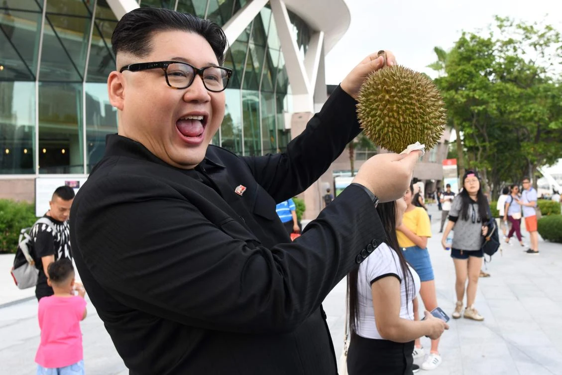 A Kim Jong Un impersonator poses holding a durian fruit in front of the Esplanade theater in Singapore on May 27, 2018. (AFP)