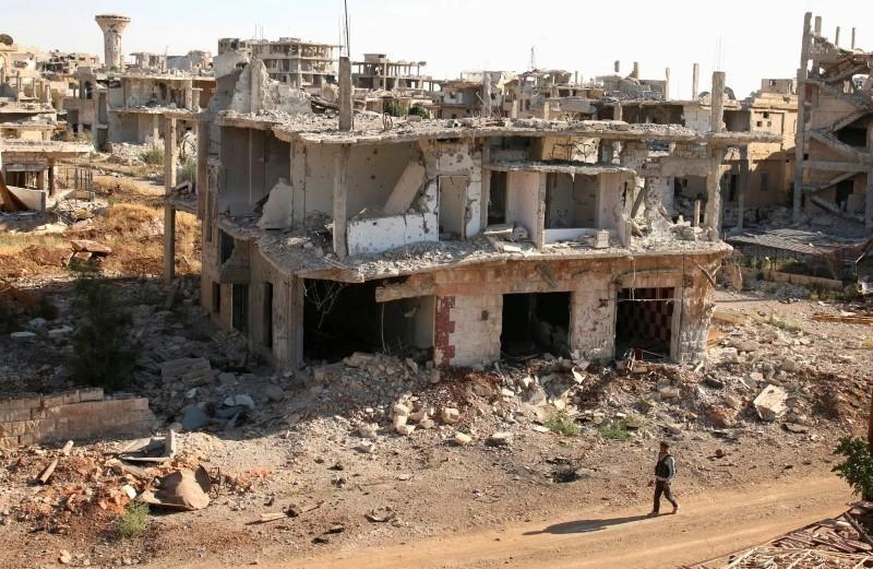 A rebel fighter walks past damaged buildings in a rebel-held part of the southern Syrian city of Deraa in this June 22, 2017 photo. (Reuters)