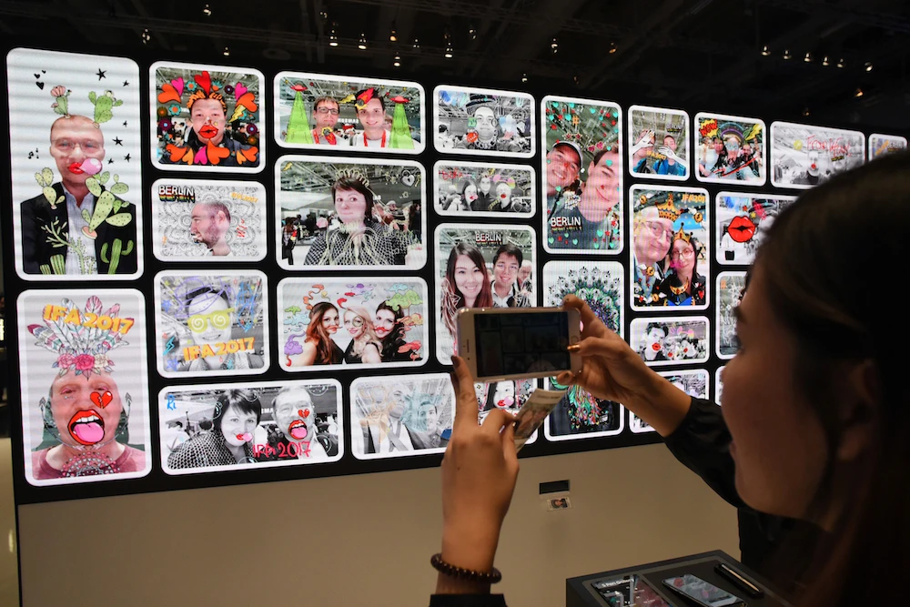 A visitor takes pictures of a photo wall at the booth of Samsung at the IFA Consumer Electronics Fair in Berlin on September 2, 2017. (AFP)