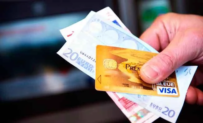 This file photo taken on February 05, 2013 in Tours (central France) shows a person holding a Visa Premier credit card and Euro banknotes. (AFP)