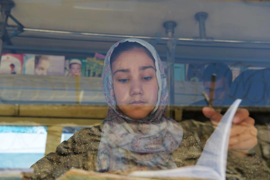 An Afghan girl reads a book in a mobile library bus in Kabul. (AFP)