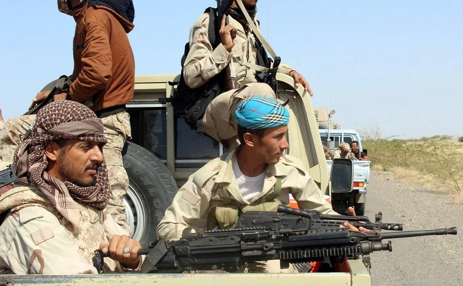 Yemeni fighters loyal to the Saudi-backed Yemeni president ride in the back of a pickup truck on a road. (AFP)