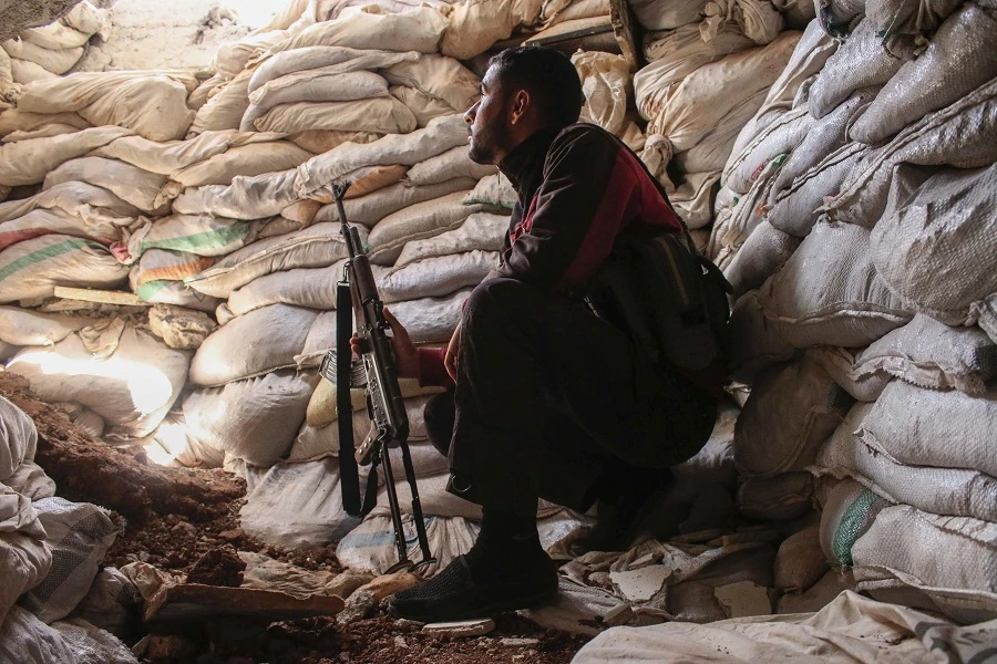 A Syrian rebel fighter sits holding a Kalashnikov assault rifle in a fortified area near the frontlines at a rebel-held area in the southern Syrian city of Daraa on June 2, 2018. (AFP)