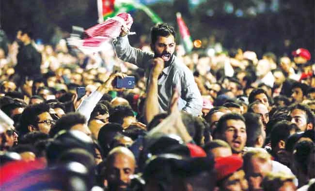 Jordanian protesters shout slogans and raise a national flag during a demonstration outside the Prime Minister’s office in the capital Amman late on Saturday. AFP