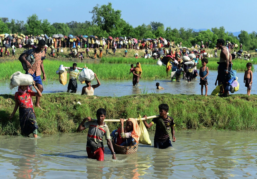 In this file photo taken on October 16, 2017 Rohingya refugees carry a woman over a canal after crossing the Naf River as they flee violence in Myanmar to reach Bangladesh in Palongkhali near Ukhia. (AFP photo)
