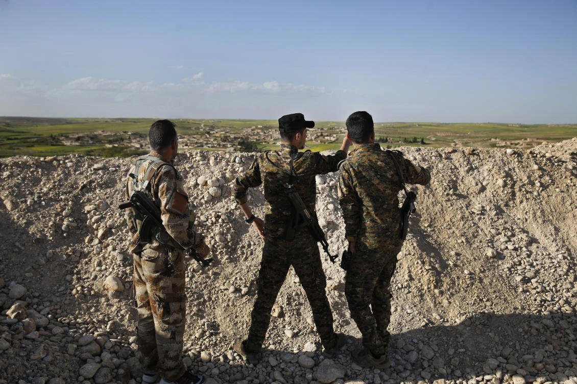 File photo showing fighters from the U.S-backed Syrian Manbij Military Council stand behind a sand barrier as they look toward Turkish-backed fighters’ position at the front line north of Manbij town, Syria. (AP)