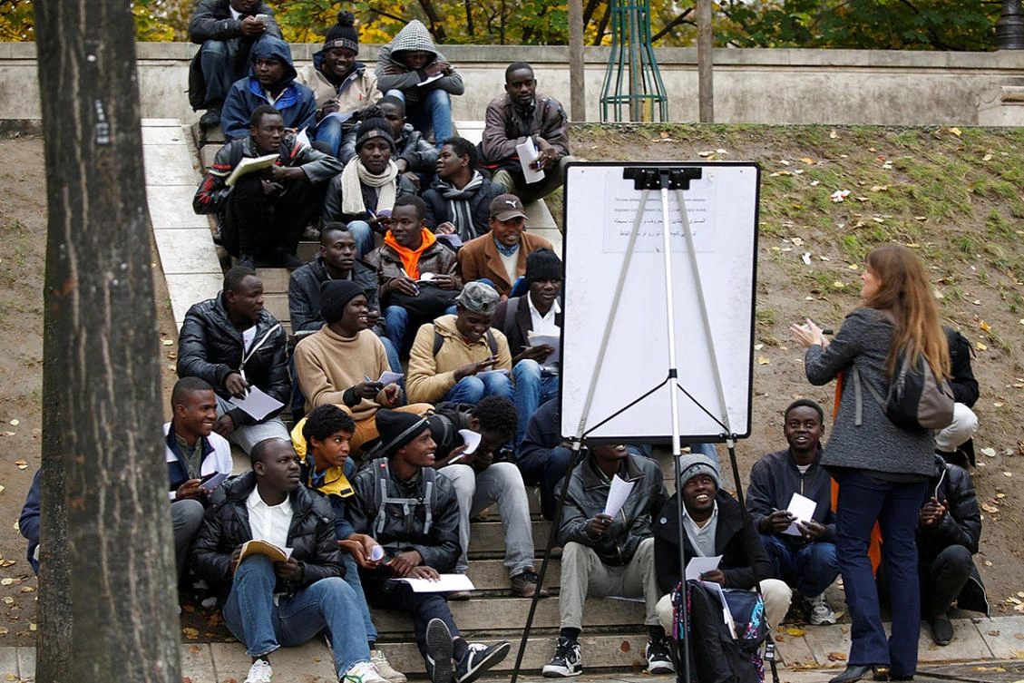 Migrants and refugees attend a French lesson near their makeshift camp in Paris. France is to double the number of lessons on offer to refugees to help them integrate. (Reuters)