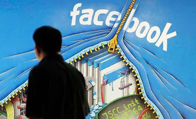In this June 11, 2014, file photo, a man walks past a mural in an office on the Facebook campus in Menlo Park, Calif. (AP)