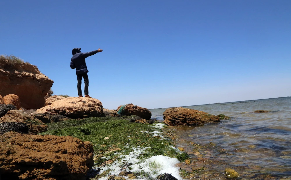 A man points toward the Mediterranean sea in Tunisia's Kerkennah Islands off Sfax on June 5, 2018. More than 65 migrants drowned in the Mediterranean on June 3, the majority off the coasts of Tunisia. Survivors said there were at least 180 people on board when the overloaded fishing vessel began to sink late Saturday night near Tunisia's Kerkennah Islands off Sfax. (AFP)