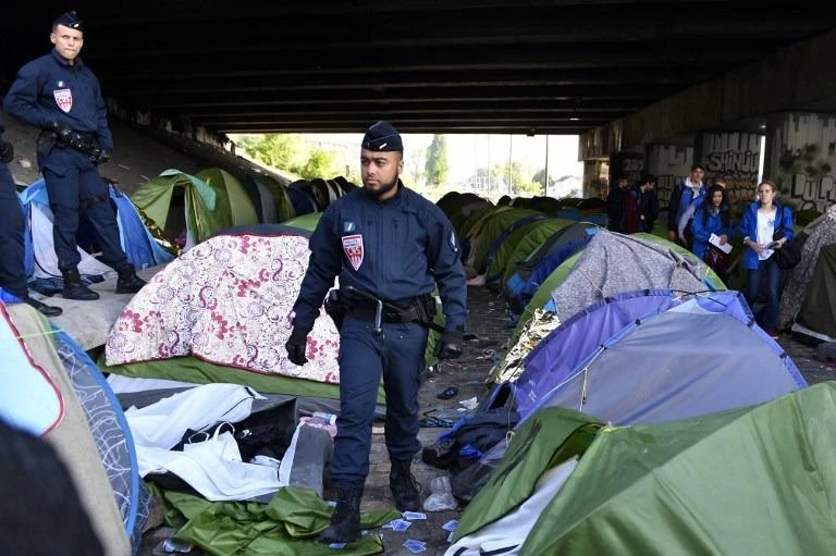 French police officers inspect tents left behind by migrants following the evacuation of the Millenaire makeshift camp along the Canal de Saint-Denis near Porte de la Villette, northern Paris, France. (AFP)