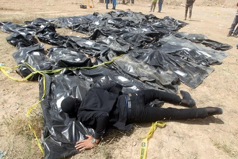 An Iraqi man cries over body-bags containing the remains of people believed to have been slain by Daesh at the Speicher camp in Tikrit, Iraq. An Iraqi refugee in France has been arrested in Paris and indicted over his alleged involvement in the massacre. (AFP)