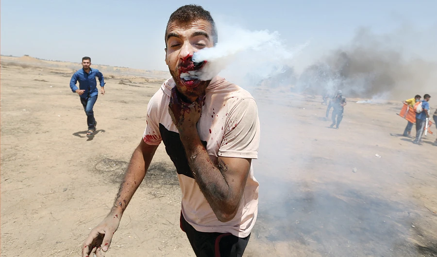 A protester is hit in the face with a tear gas canister fired by Israeli troops at the Gaza border on Friday. (Reuters)