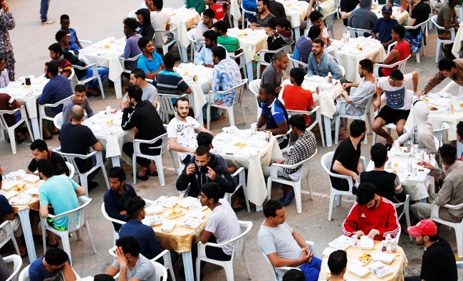 Muslims migrants wait to have their Iftar meal during the holy fasting month of Ramadan, at a detention centre in Tripoli, Libya May 30, 2018. (REUTERS)