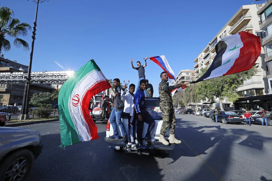 Syrian government supporters wave Syrian, Iranian and Russian flags as they chant slogans. (AP)