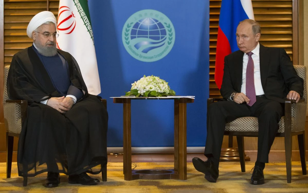 Russian President Vladimir Putin, right, speaks to Iranian President Hassan Rouhani during their meeting in Qingdao, China, Saturday, June 9, 2018. (AP)