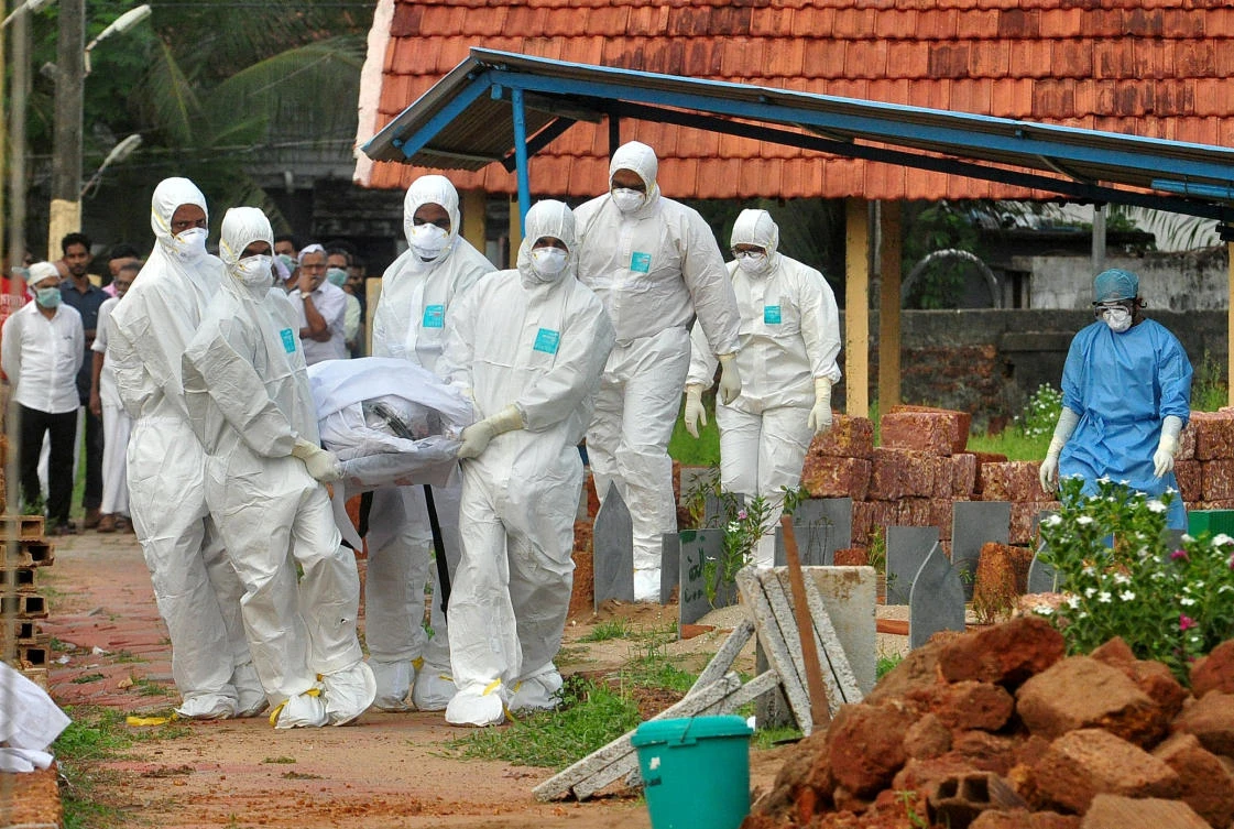 In this file photo, doctors and relatives wearing protective gear carry the body of a victim, who lost his battle against the brain-damaging Nipah virus, during his funeral at a burial ground in Kerala, India. (Reuters)