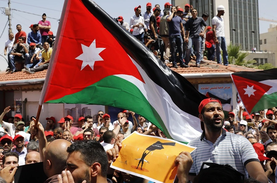 Jordanian protesters wave national flags and shout slogans during an anti-austerity rally, on June 6, 2018, in front of the Labor Union offices in Amman. (AFP)