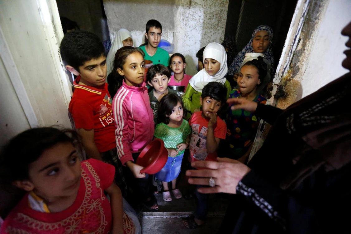 Children wait for meals provided through the initiative, Family Kitchen, which packages excess foods from five-star hotels to underprivileged families during the holy month of Ramadan, in Al-Baqaa Palestinian refugee camp, near Amman, Jordan, June 11, 2018. (Reuters)