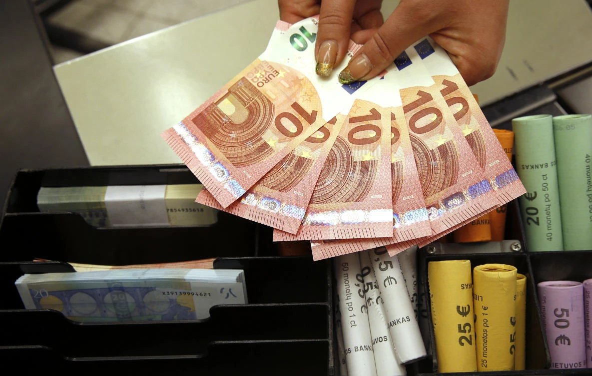 Euro coins and banknotes are shown by a salesclerk at a shop. (Mindaugas Kulbis/AP)
