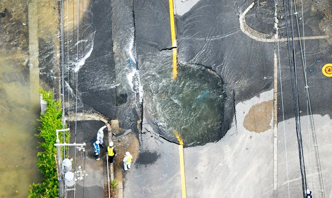 Water floods out from crack in the road, following an earthquake in Takatsuki, Osaka, Monday, June 18, 2018. (AP)