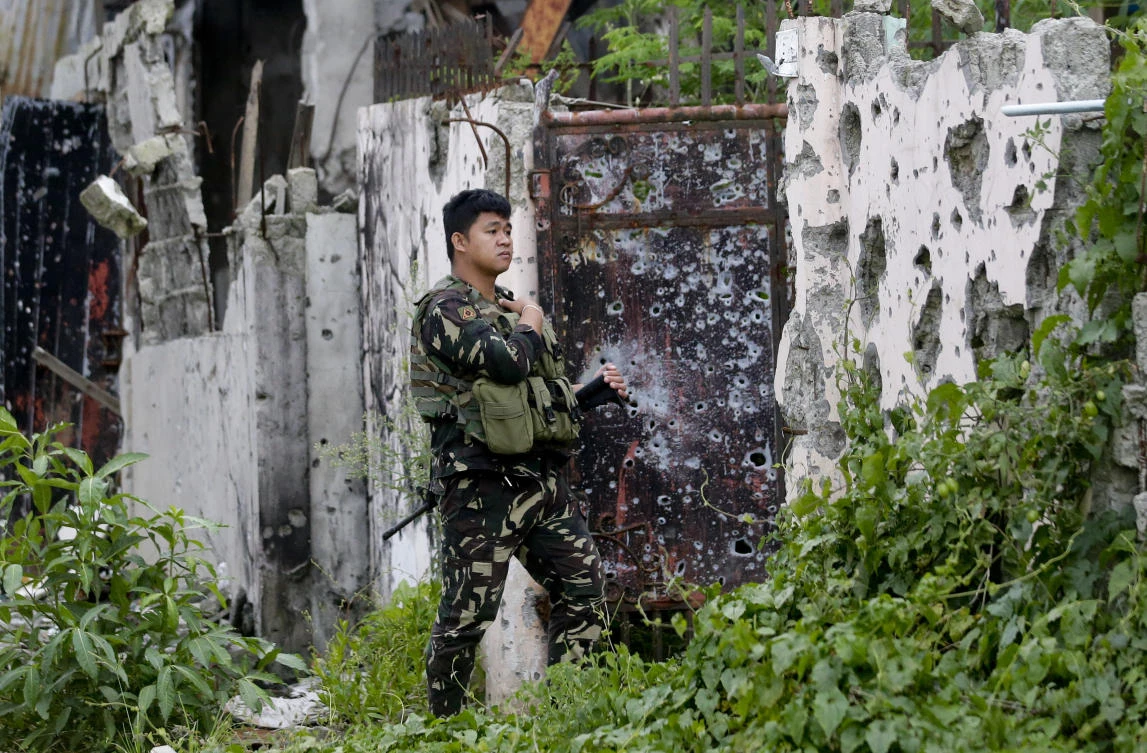 A soldier stands beside bullet-riddled gate and walls in an area where government troops battled extremists in Marawi city, southern Philippines. (Aaron Favila/AP)