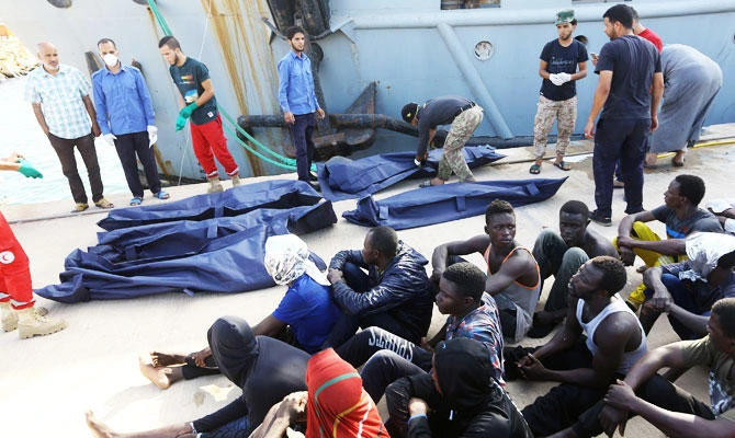 African migrants rescued from a ship off the coast of Zuwara, about 130 kilometres west of the Libyan capital Tripoli, sit alongside of bodies of others who died, at the dock in the capital's naval base on June 18, 2018. (AFP)