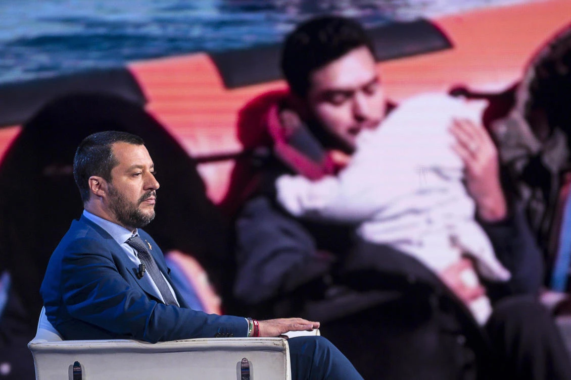 Italian Interior Minister Matteo Salvini, backdropped with a photograph of migrants being rescued at sea, on a RAI state television talk show. Salvini said a German charity vessel flying a Dutch flag should take rescued Libyan migrants to the Netherlands. (AP Photo)